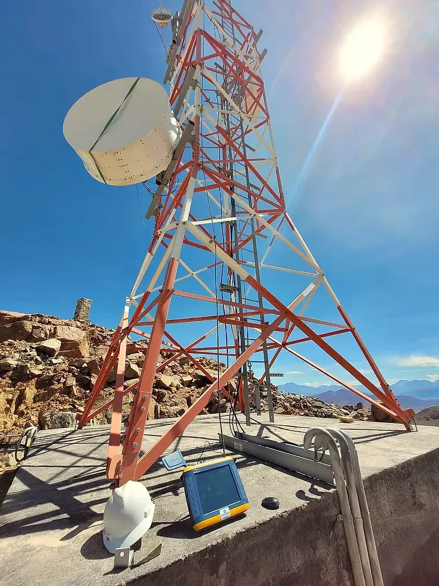 Torre de telecomunicaciones con antena de microondas e instrumento de medición en terreno
