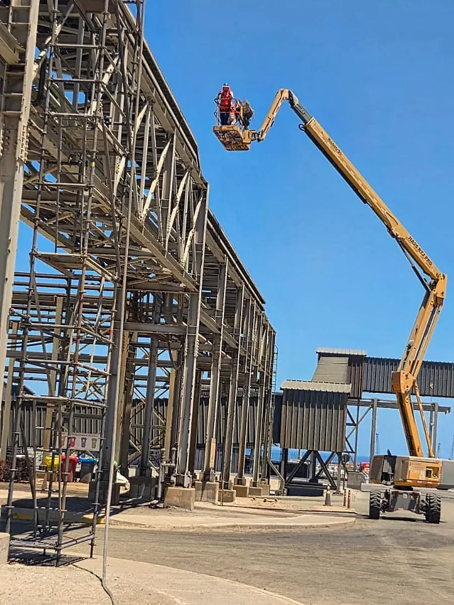 Estructuras de una planta industrial con técnicos trabajando en un brazo elevador